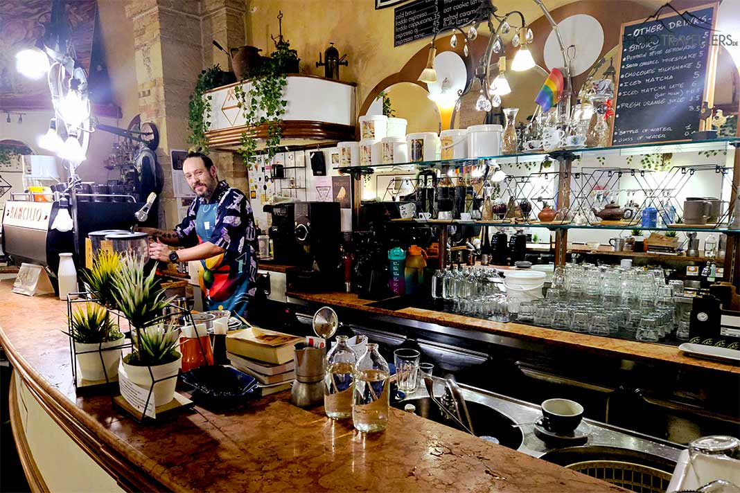 Ein Mann am Tresen des Caffé dell'Arte und lächelt in die Kamera