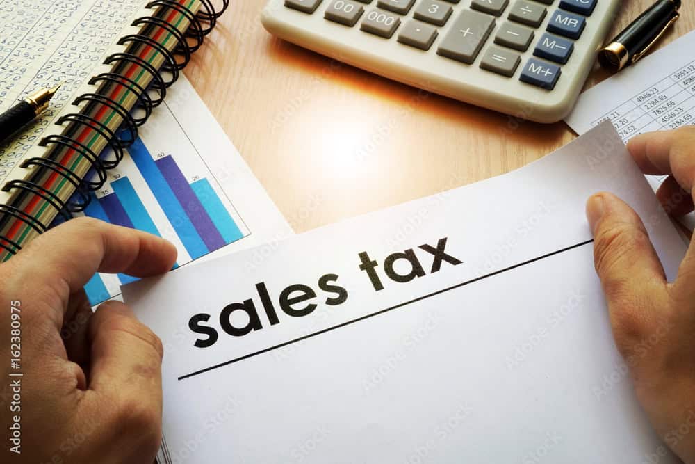 Hands holding documents with title sales tax.