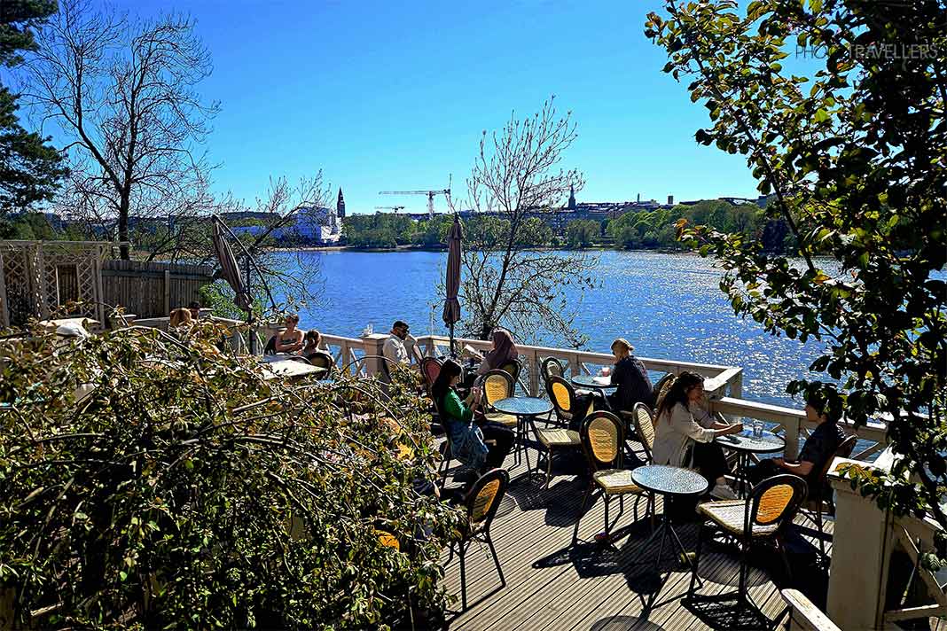 Gäste sitzen auf der Holzterrasse des Café Café Taideterassi oberhalb der Bucht von Töölö in Helsinki