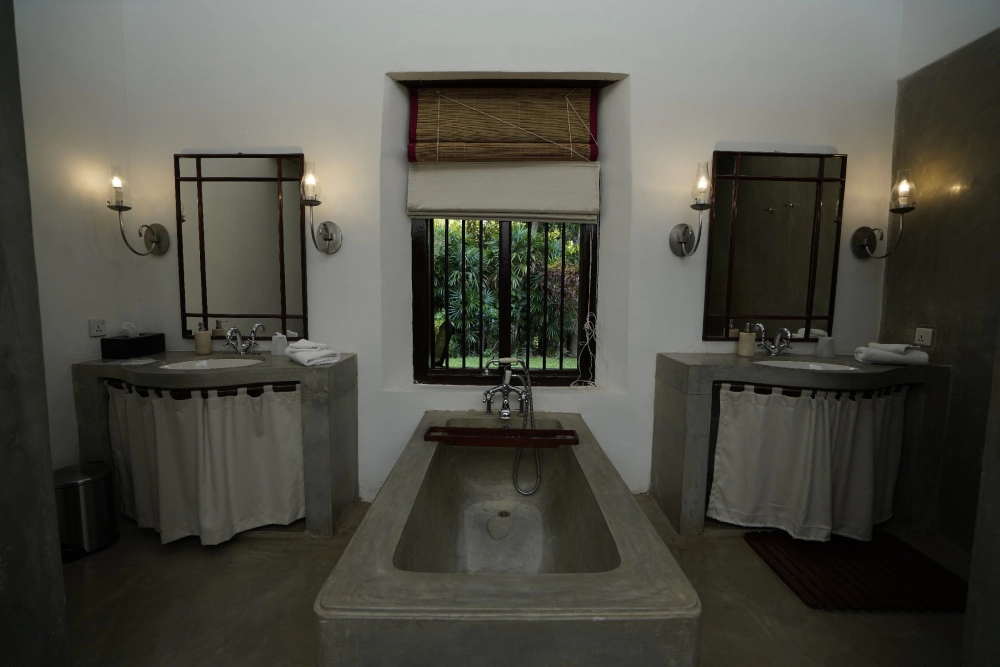 Interior of the Red Spot Duke room's bathroom in Adigar's Manor, showcasing a tub and a sink.