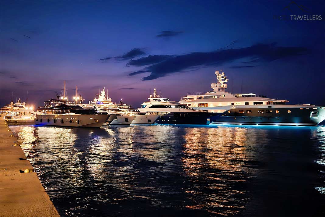 Beleuchtete Luxusyachten ankern nebeneinander im Nachtlicht in Spetses