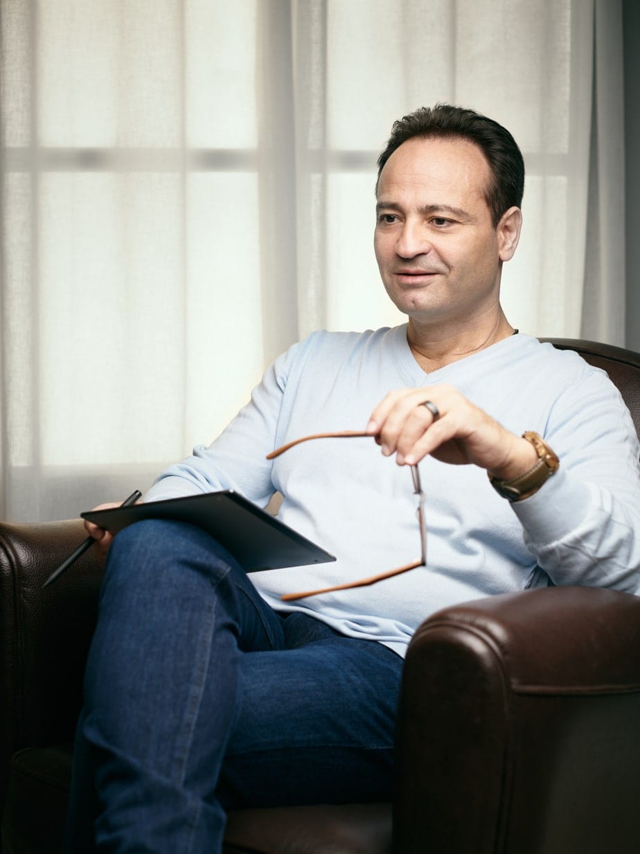 Michaël Cohen Web 5 Michaël Cohen seated in a leather armchair, holding his glasses and a tablet
