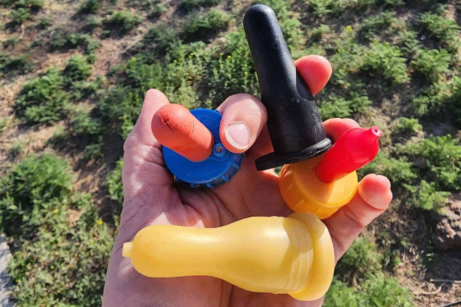 a hand holding different nipple for feeding bottle baby goats
