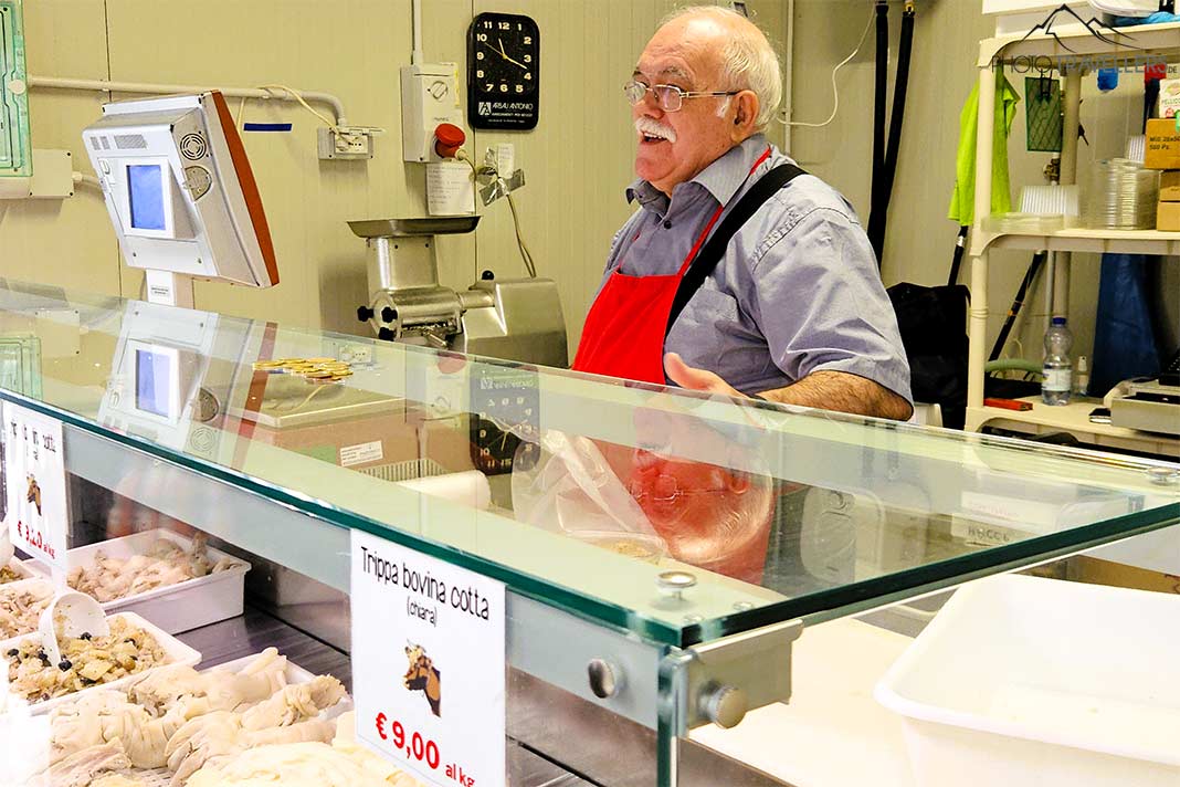 Ein älterer Verkäufer steht hinter seinem Fischstand und lacht
