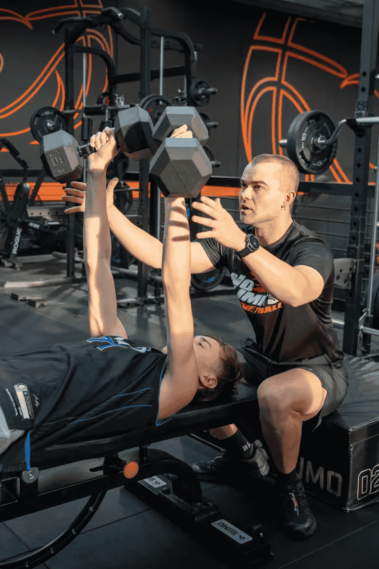 Dumbbell shoulder press exercise at No Limits Basketball gym.