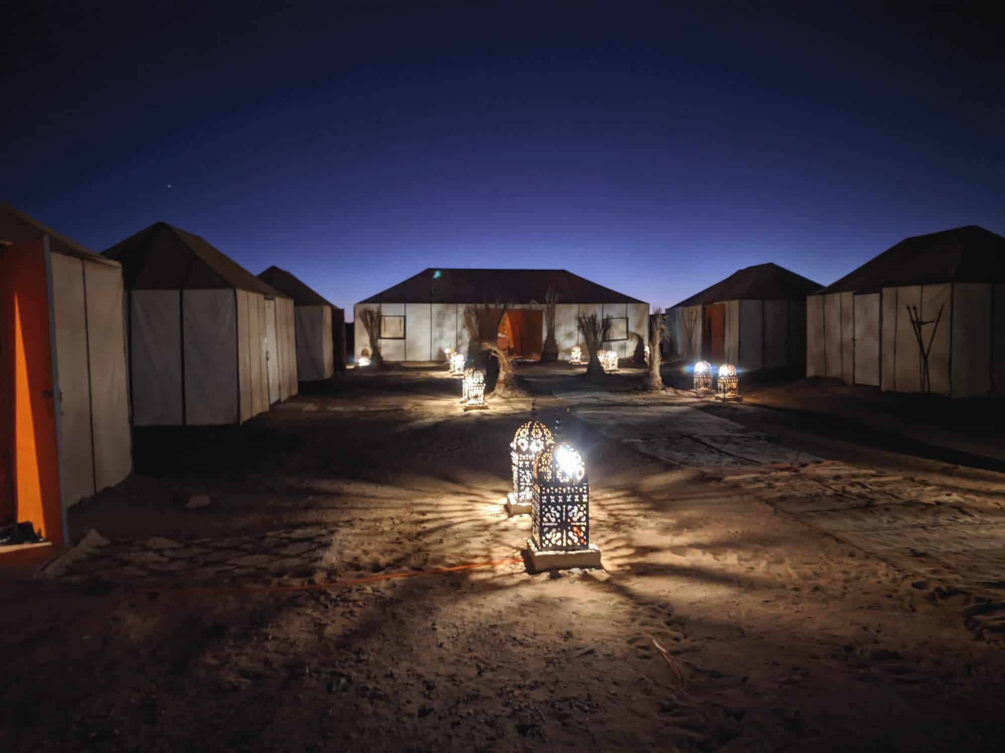Refugios en el desierto con iluminación nocturna y cielo estrellado.