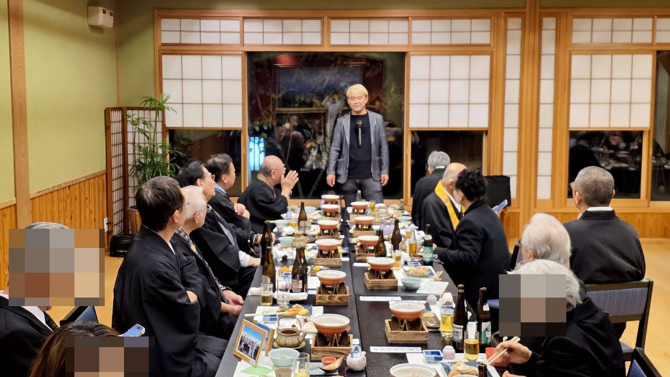 笑顔で偲ぶ大切な時間。先代御住職の三回忌法要にてマジックをお届けしました! 1 料亭「茜月」にて、先代御住職の三回忌法要後の会食でマジックを披露するコンプレッサー。御住職や参列者の皆様が間近で見守る温かい雰囲気。