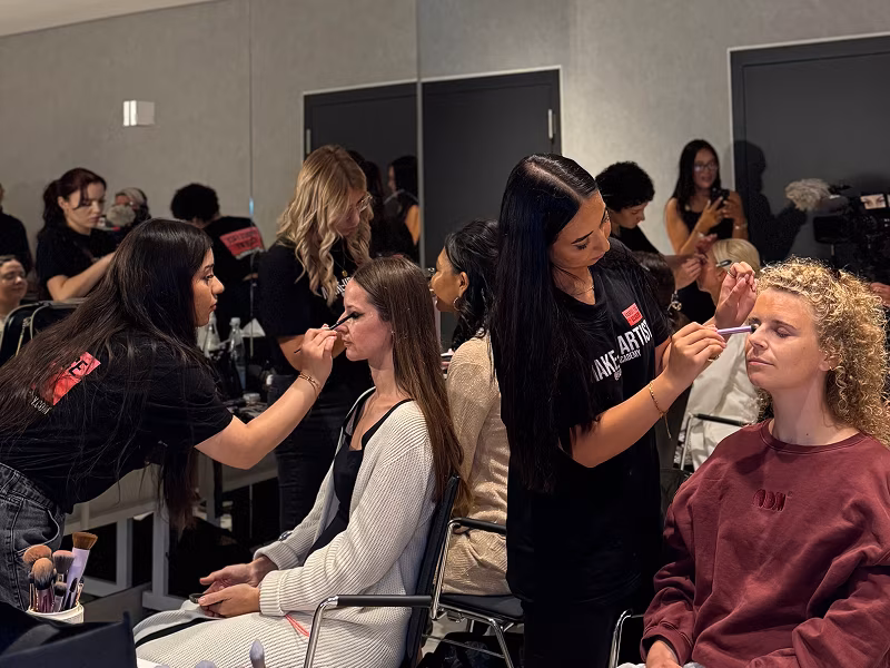 Schülerinnen der Famous Face Academy schminken Models auf einem Event