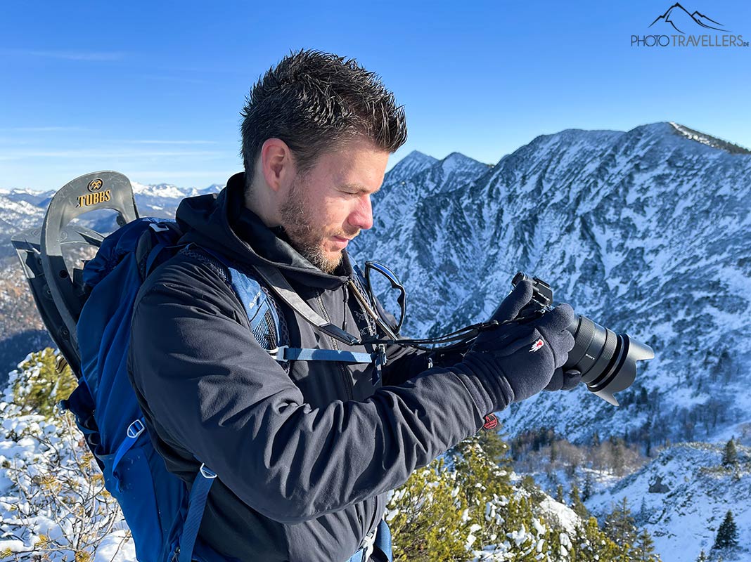 Flo auf einem Berggipfel mit Kamera und dem Merino Liner Pro Fotohandschuh