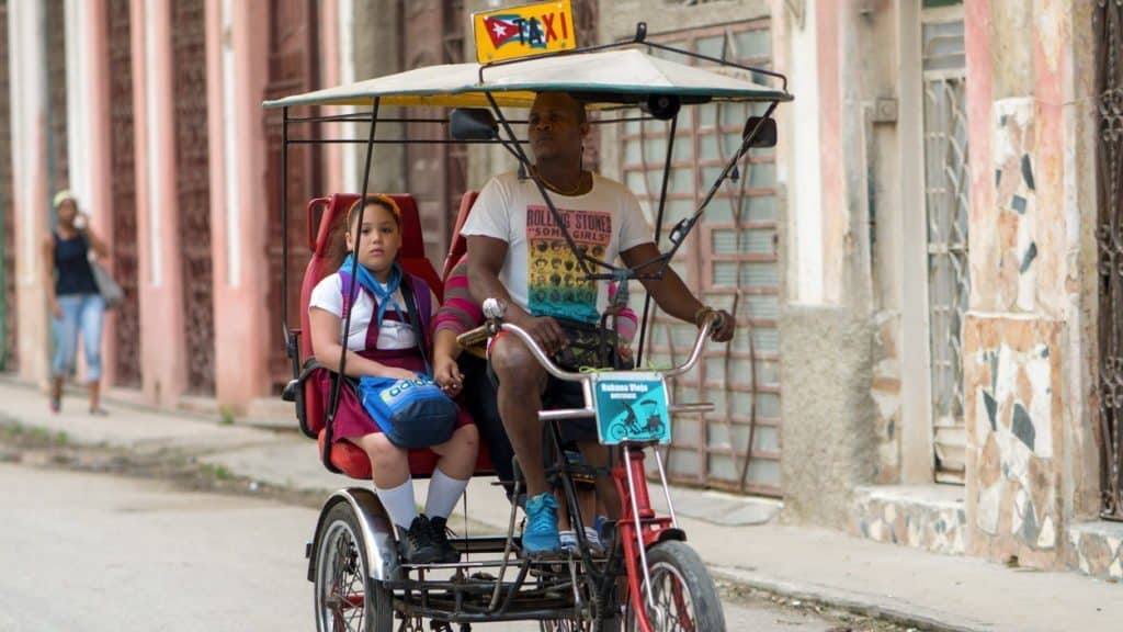ojciec i dziecko w rikszy w drodze do szkoły w Hawanie