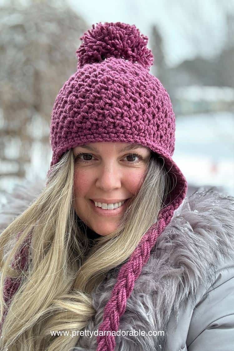 lady wearing pink crochet hat with earflaps and pompom