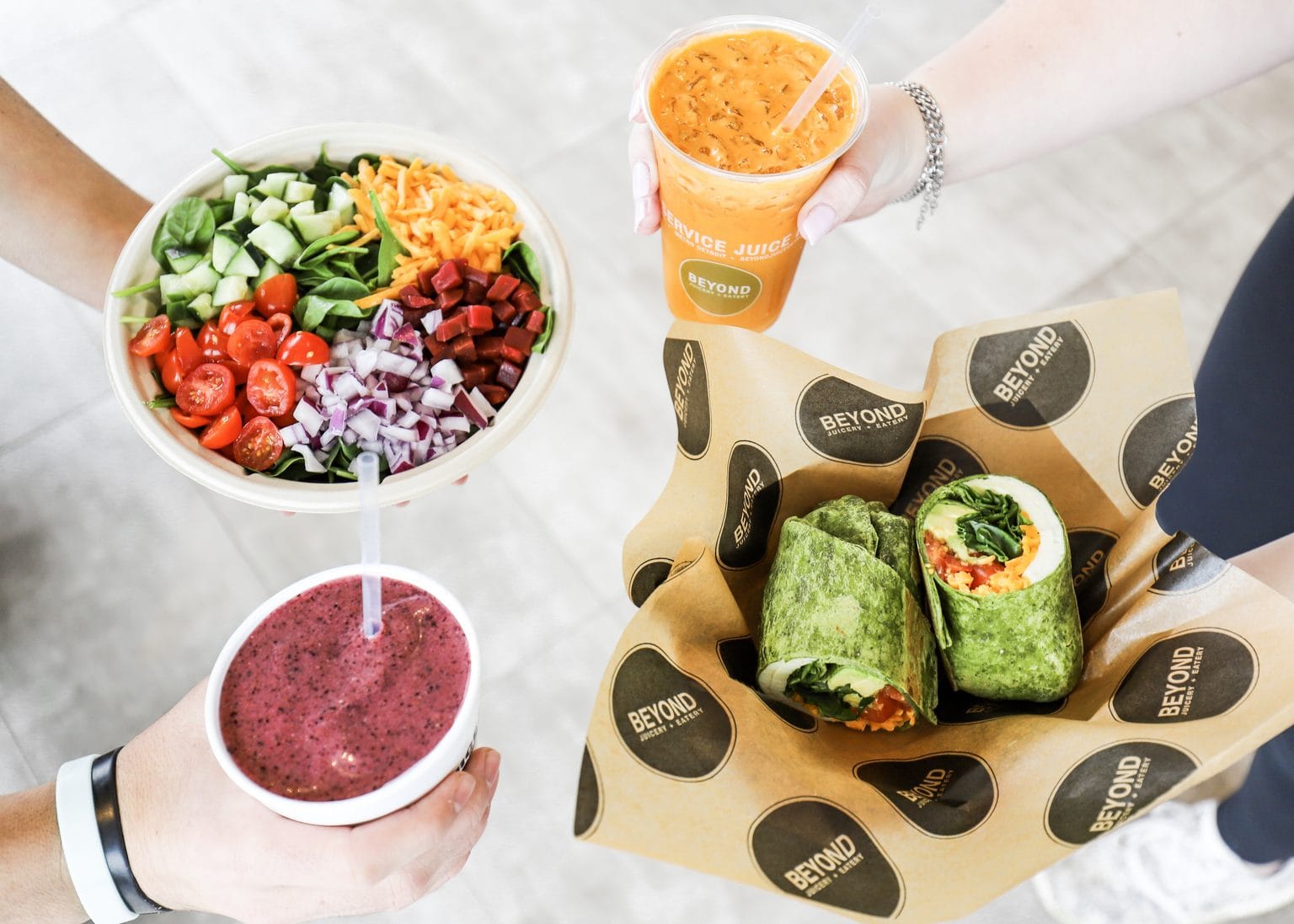 Overhead view of a Beyond Juicery + Eatery salad, smoothie, juice, and wrap spread