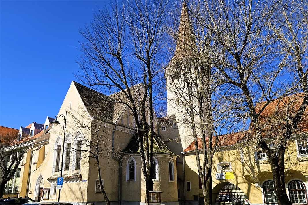 Das helle Seitenschiff und der Turm der evangelischen Kirche Sibiu wird voJon Bäumen umrahmt