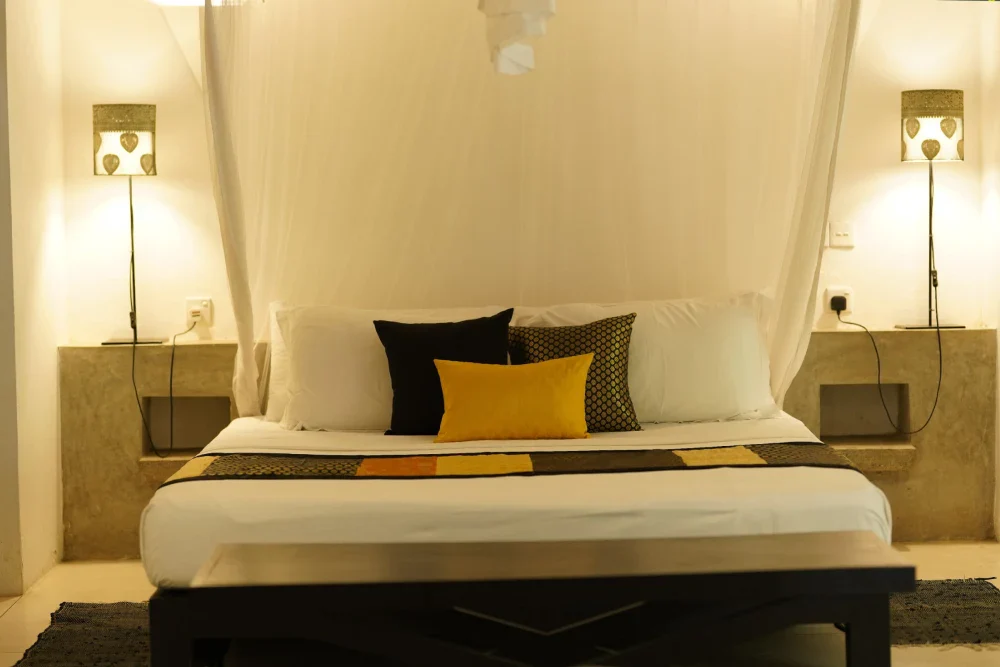 A luxurious bed with a canopy in the Black Raja bedroom of Adigar's Manor, showcasing elegant decor and rich fabrics.