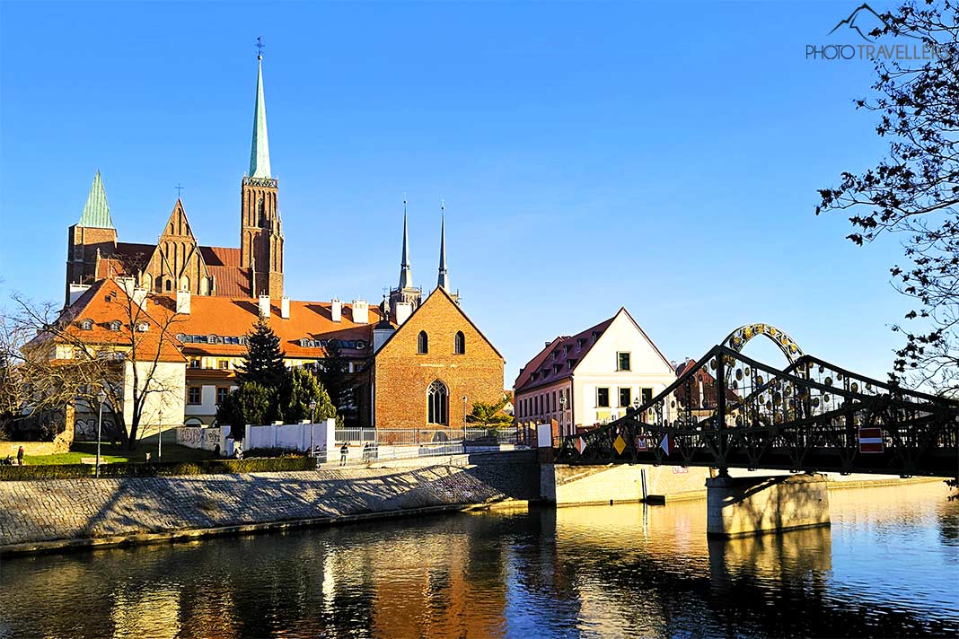 Backsteinhäuser und eine schmale Eisenbrücke über der Oder mit dem Dom im Hintergrund