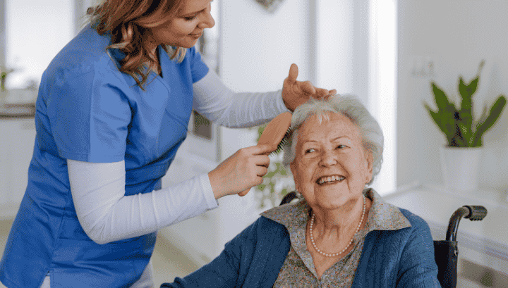 Personal and Daily Living Assistance | Comprehensive Elderly Care Services Smiling senior receiving grooming assistance from a caregiver, reflecting personal and daily living assistance and elderly care services.