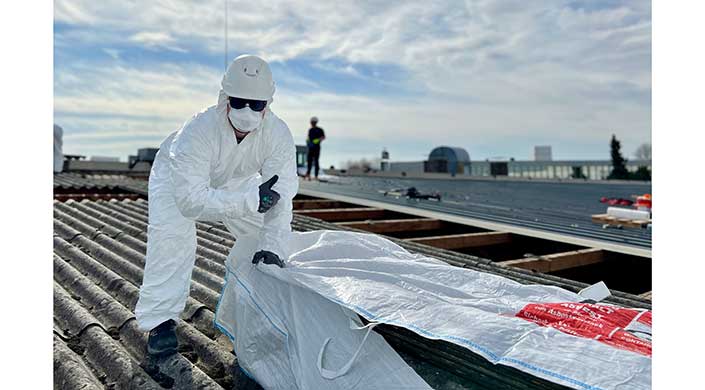 Bauarbeiter steht auf einem Dach mit Baumaterialien im Vordergrund, bewölkter Himmel.