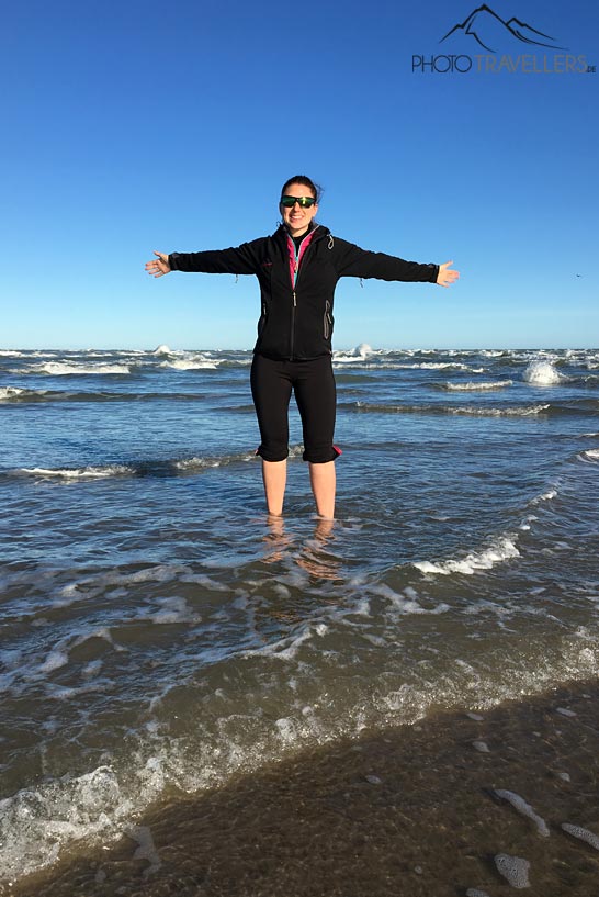 Reisebloggerin Biggi Bauer steht in Grenen im Meer, wo Nord- und Ostsee aufeinandertreffen