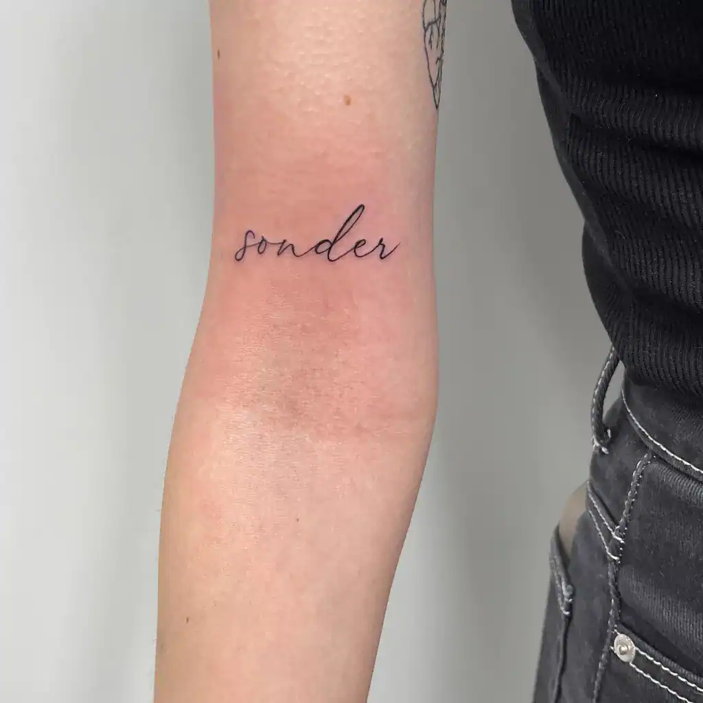 Schrift Tattoo am Oberarm oberhalb der Armbeuge