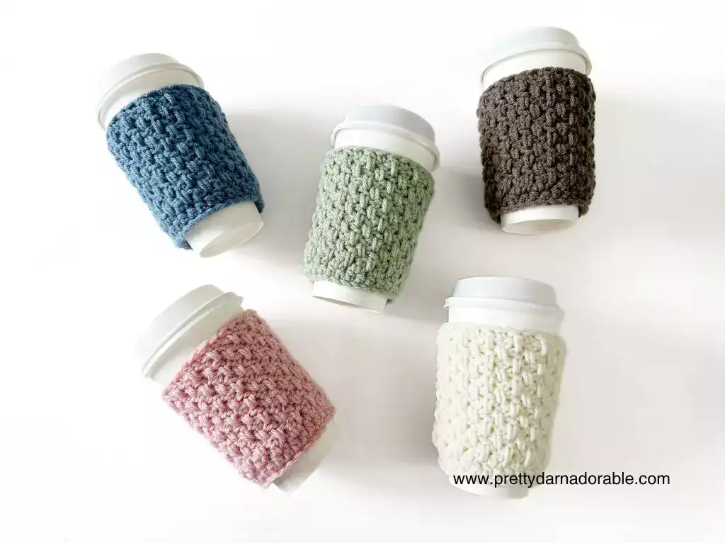 a group of crochet coffee cozies in soft pastel colours