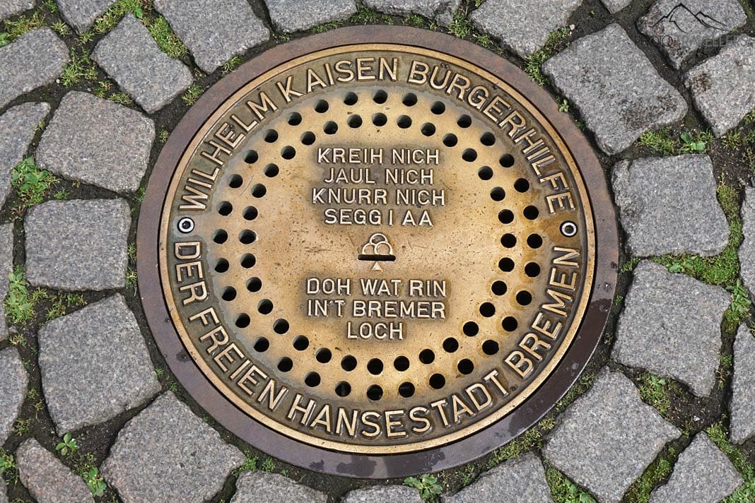 Das Bremer Loch, ein goldener Kanaldeckel mit der Aufschrift "Kreih nich, jaul nich, knurr nich, segg i aa, doh wat rin in't Bremer Loch"