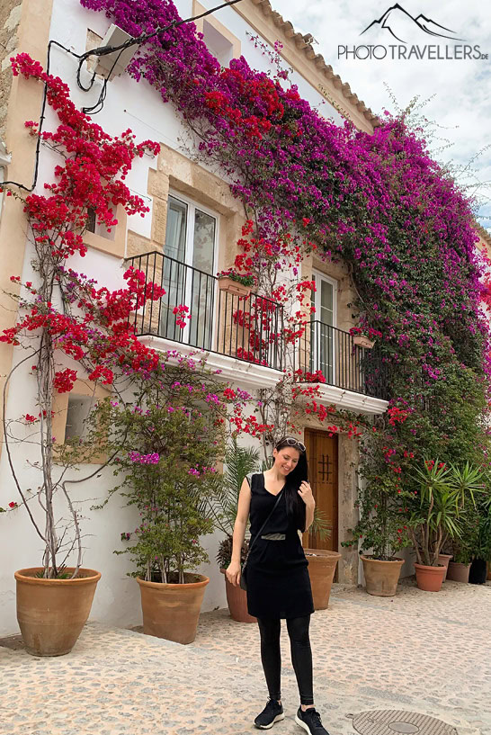 Reisebloggerin Biggi Bauer vor einer Hauswand mit roten und lila Blüten in Ibiza Stadt