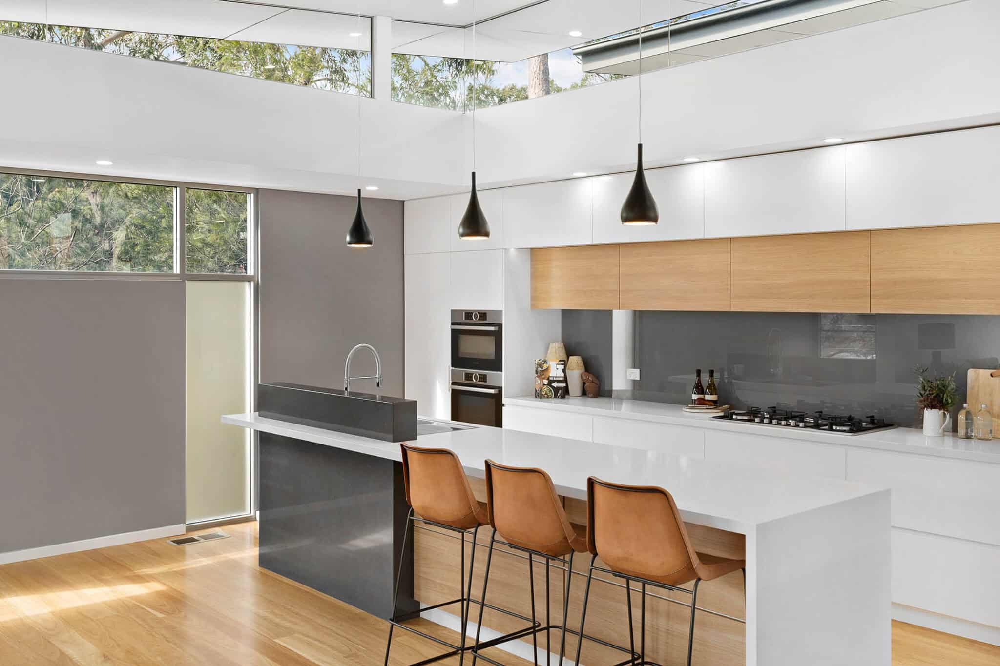 modern kitchen design in white with contrasting timber cupboards and charcoal and white coloured island bench.