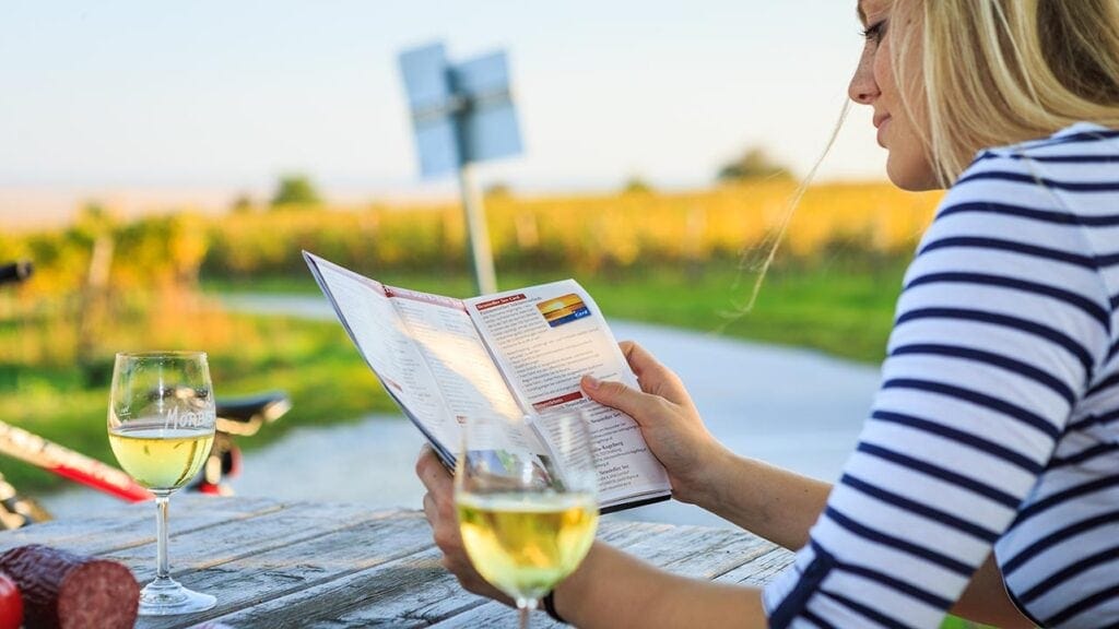 Frau liest Weinkarte am Neusiedlersee bei Sonnenuntergang.