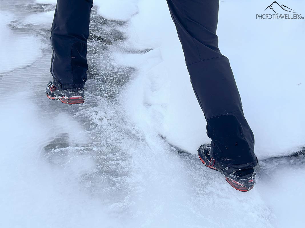 Die Beine eines Wanderers mit den Snowline Spikes Light auf einer vereisten Fläche in den Bergen