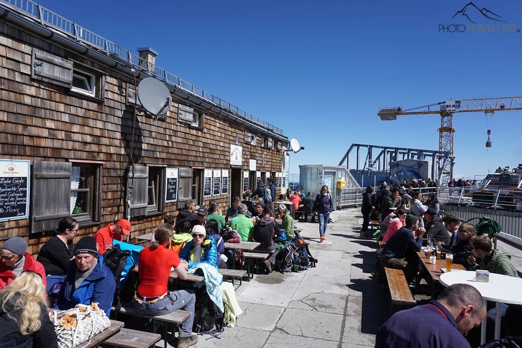 Besucher sitzen auf der Terrasse vom Münchner Haus auf der Zugspitze