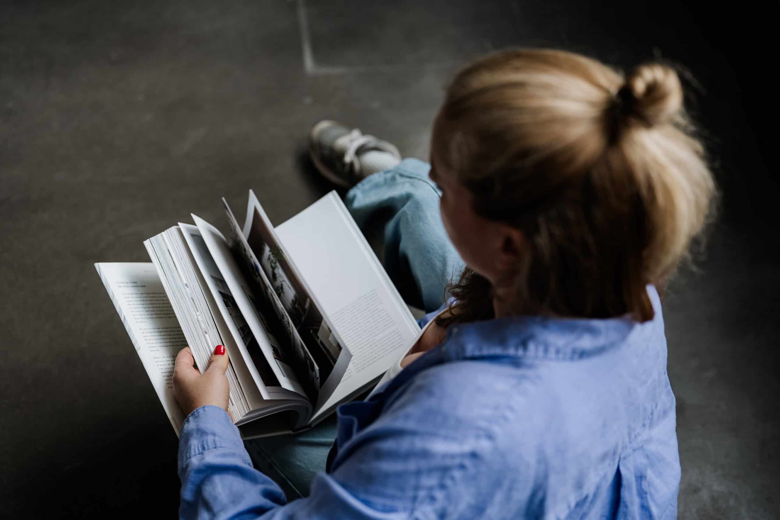 Foto als Link zur Unterseite Leistungen Hochzeitsfotografin Vera blättert durch Fotobuch beim Shooting in Köln