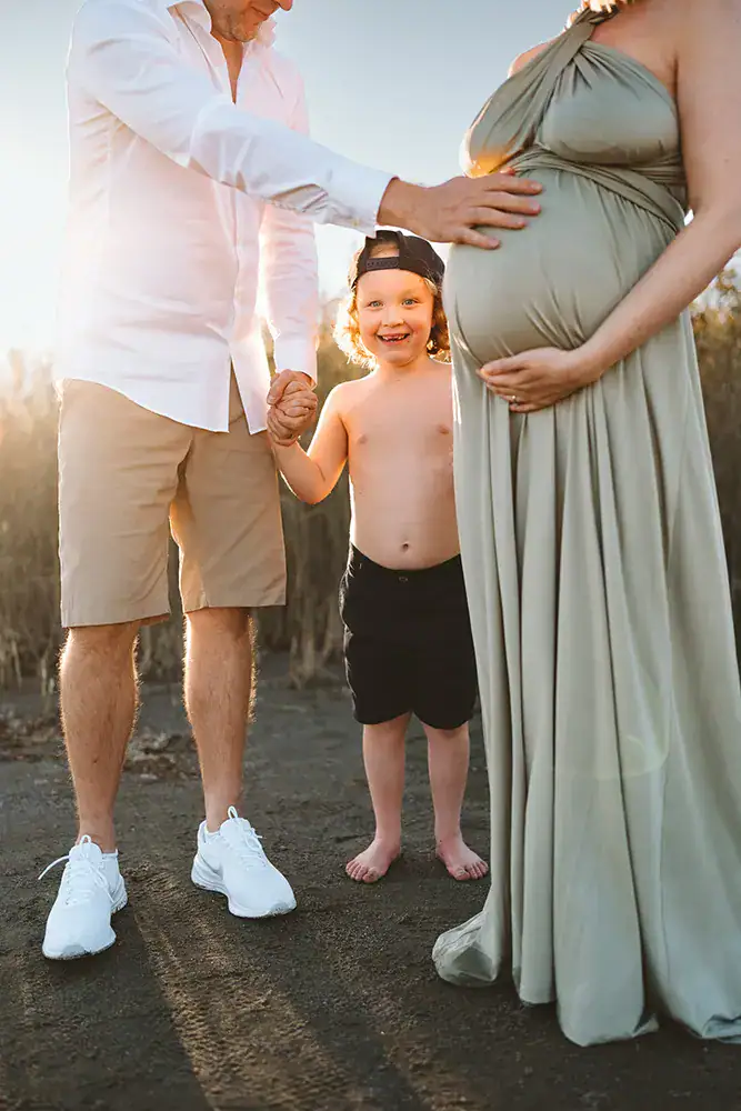 expecting mother, father and older child enjoying a beach moment together as a family in Helsinki Finland during a maternity photoshoot
