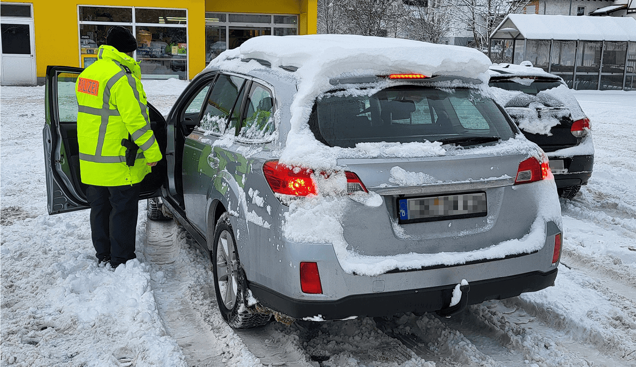 Bildnachweis: Polizeipräsidium Mittelhessen“ Polizist kontrolliert Auto im Schnee.