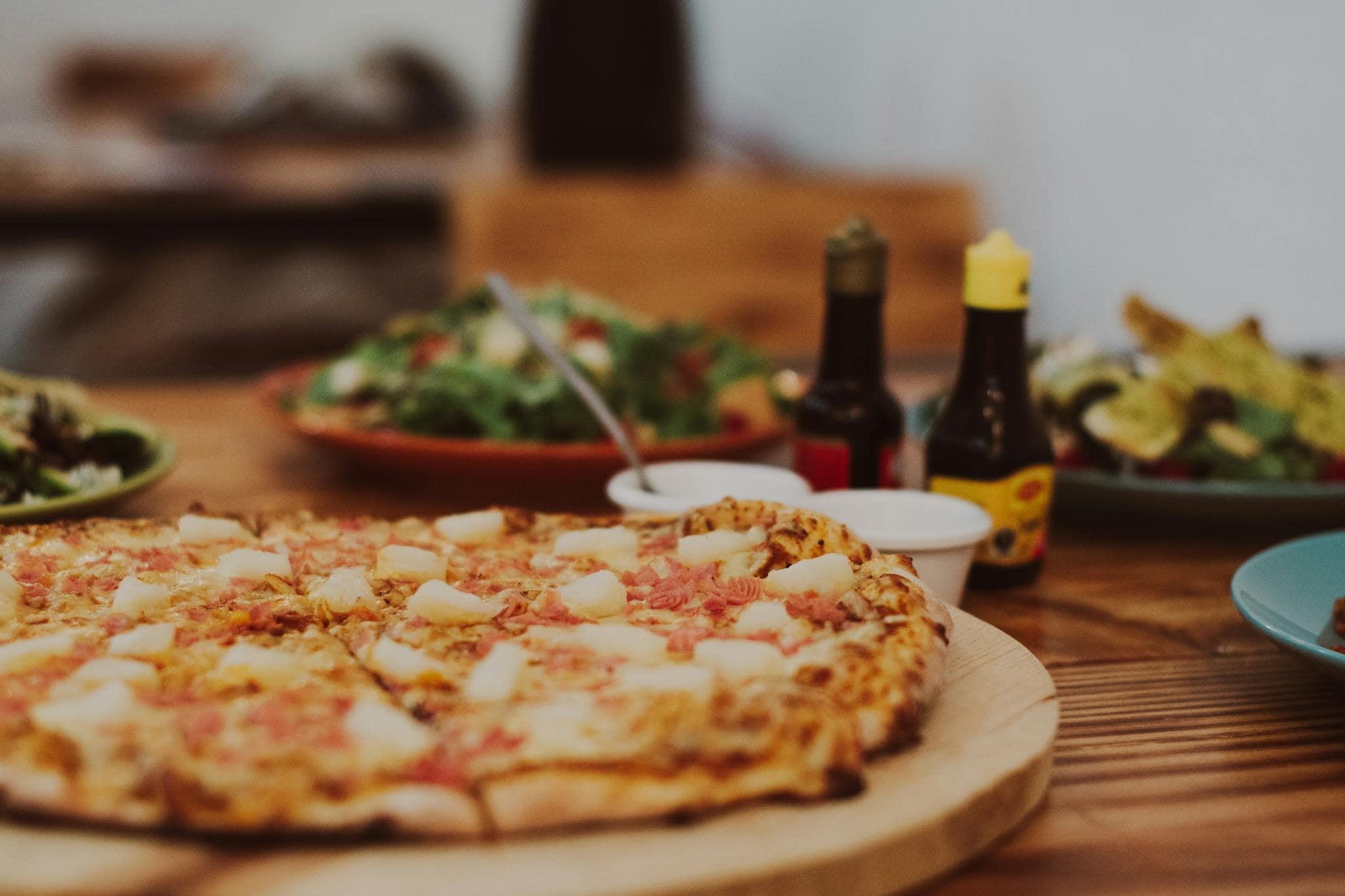 Close-up of a tasty Hawaiian pizza with pineapple and ham toppings on a wooden table.