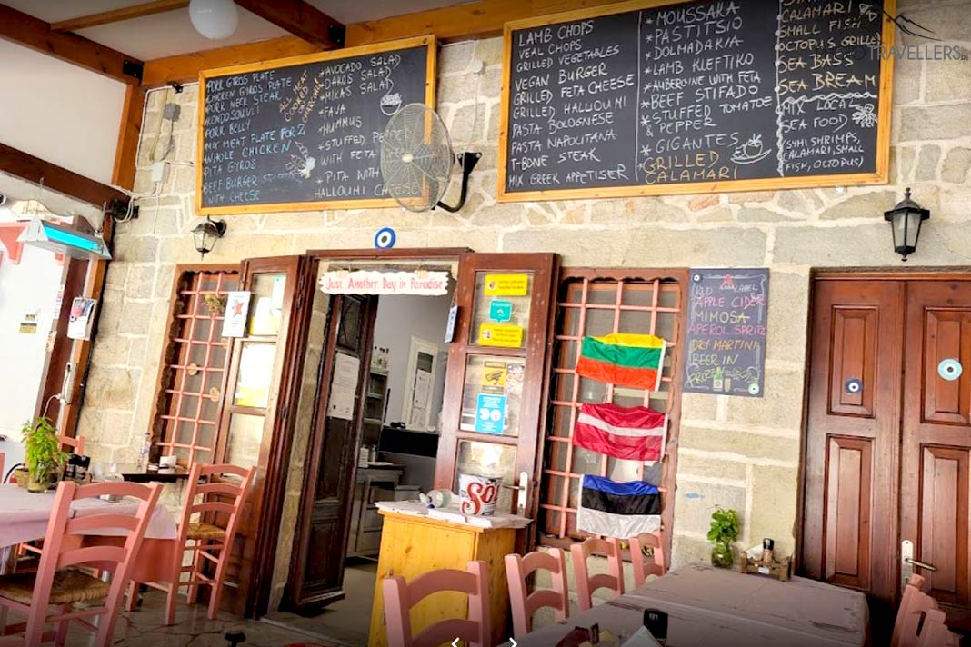 Eingangstür und Tische einer Taverne mit Speisetafeln an der Wand