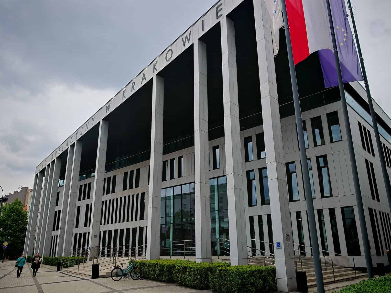 Modern building with flags and the words 'W KRAKOWIE' on the facade.