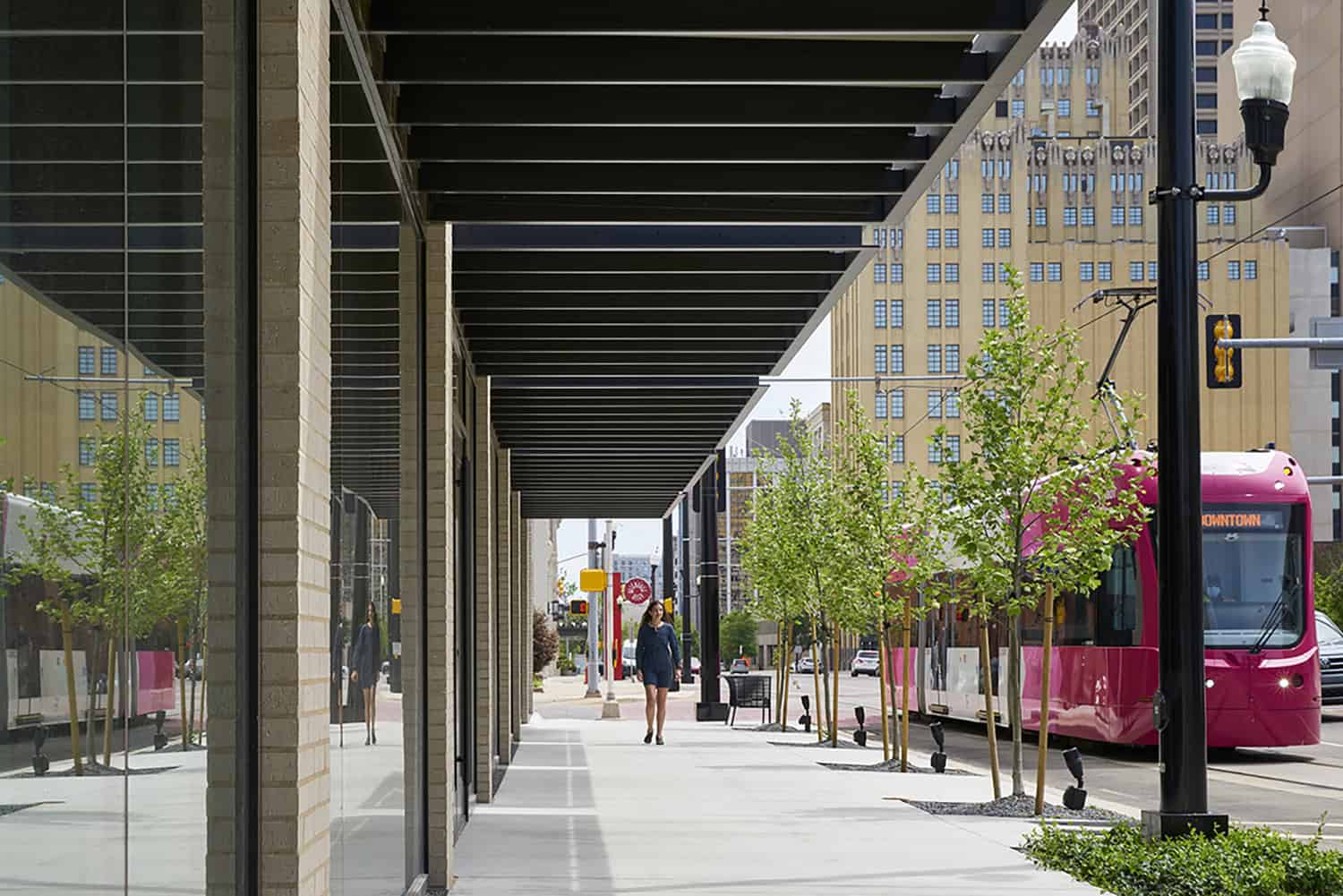 Street-level view of Heartland Headquarters in Oklahoma City, showcasing the sidewalk, architectural overhang, and passing streetcar.