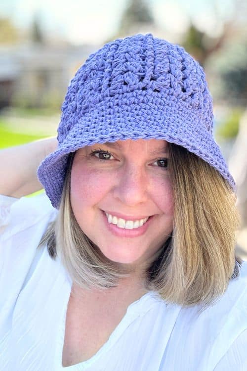 a smiling person wearing a purple crochet bucket hat