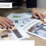 Persona observando imágenes de cocinas sobre una mesa, explorando diferentes estilos y diseños para inspirarse en la renovación de su cocina.