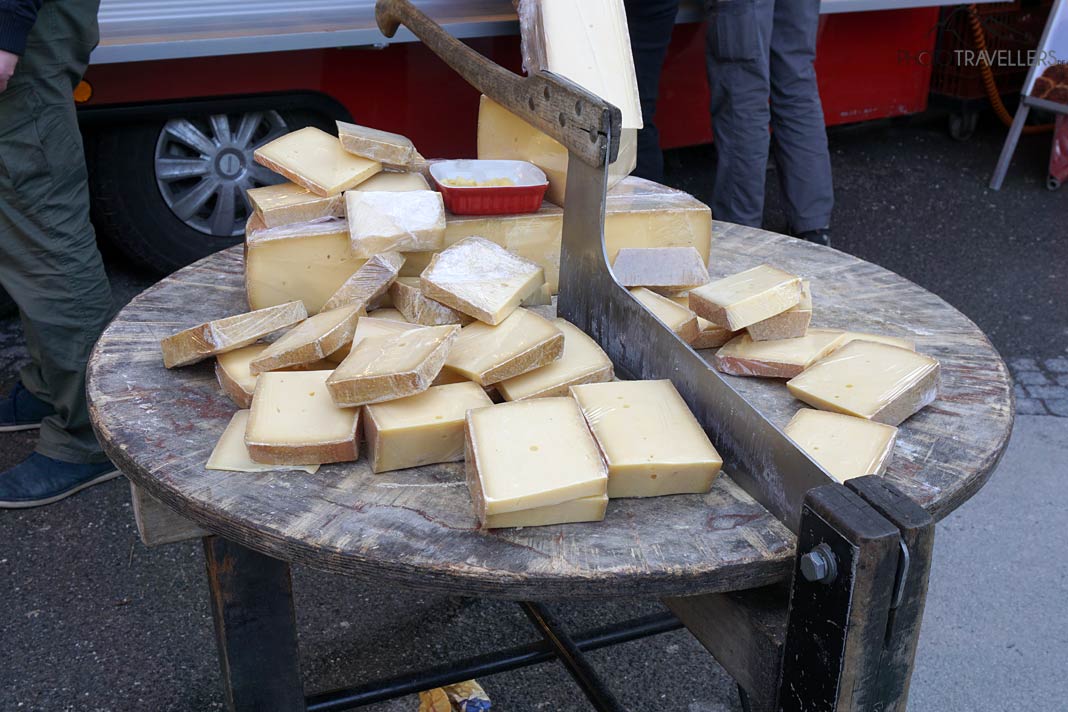 Ein Tisch mit verschiedenen Käsestücken und einem Beil auf dem Markt in Salzburg
