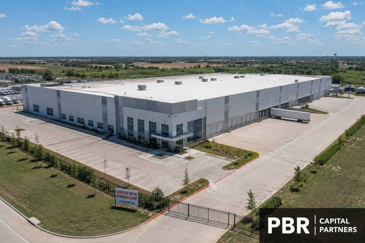 Aerial view of a large industrial warehouse under new ownership