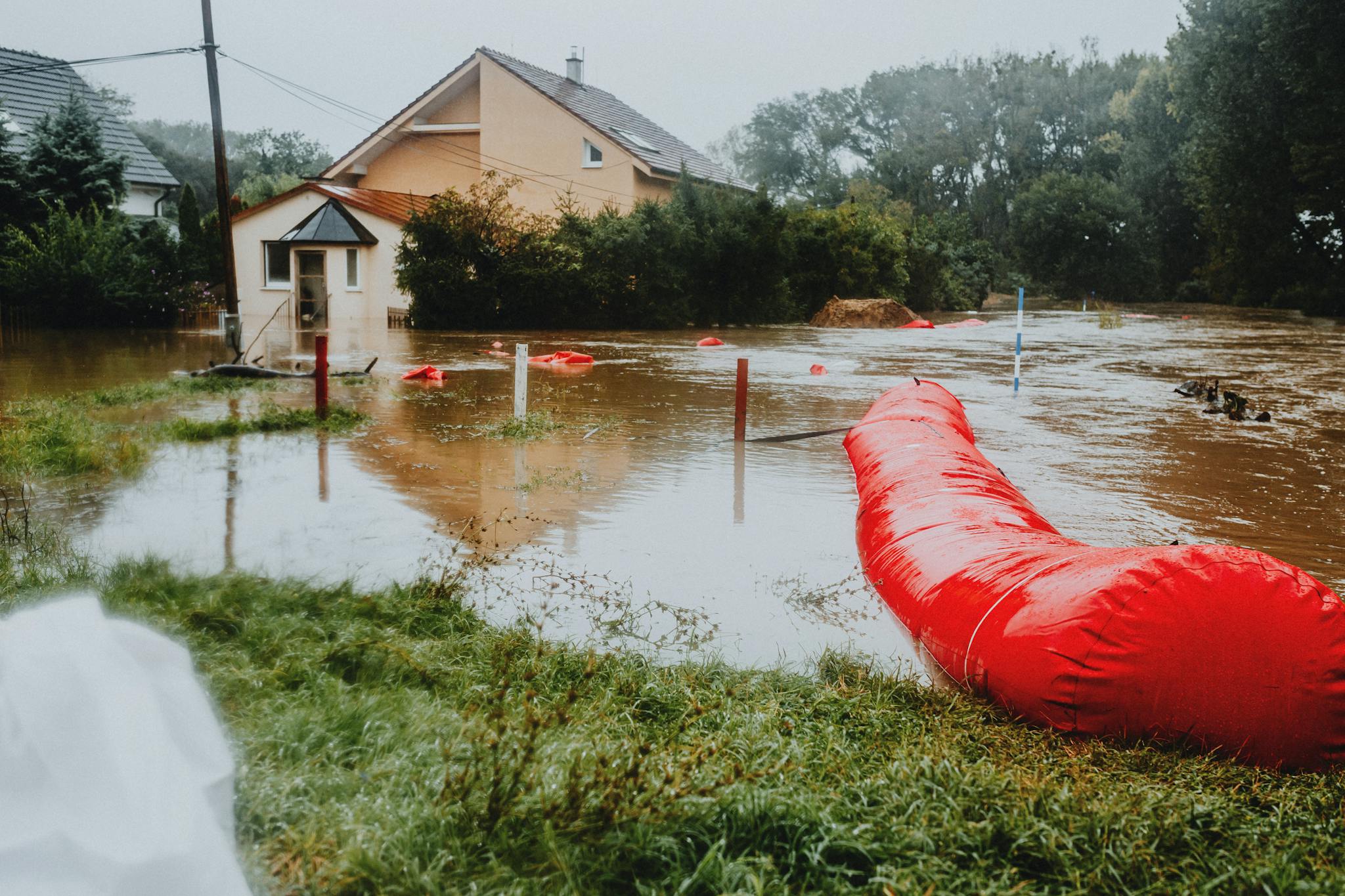 Flooded residential area protected by red flood barriers, showing severe weather impact.