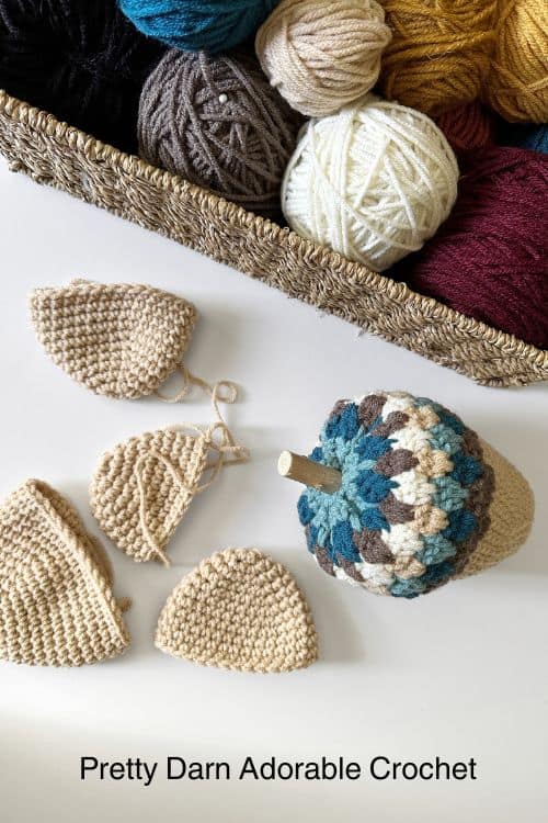 Colorful yarn in a basket sits above crocheted pieces and a multicolored acorn; text: Pretty Darn Adorable Crochet. Free crochet pattern