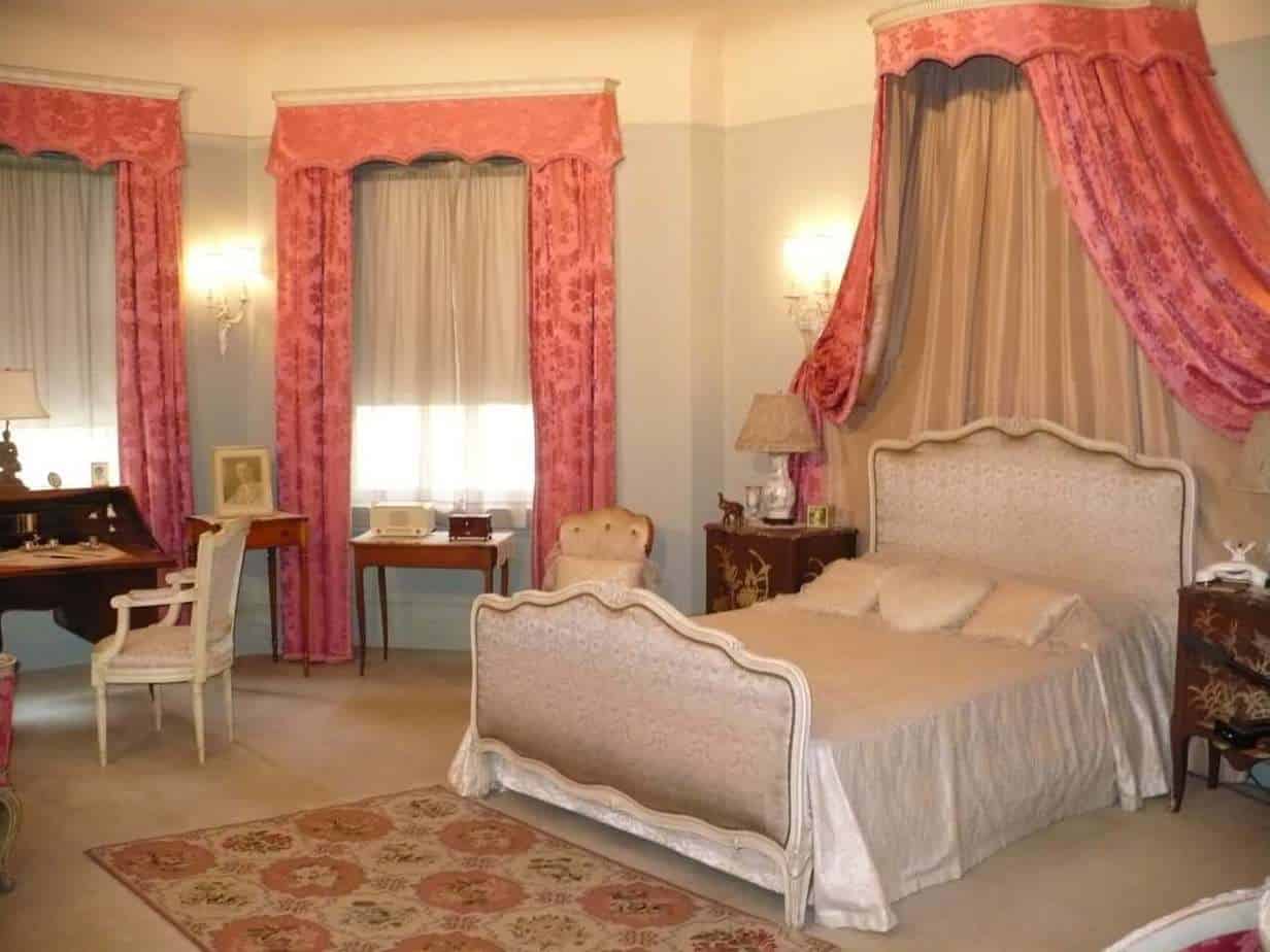 master-bedroom-1-by-Marilyn-Thompson Vintage bedroom with ornate pink curtains and a canopy bed at The History Museum.