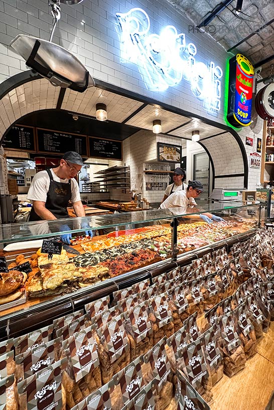 Bäcker hinter der gefüllten Theke im Antico Forno Roscioli in Rom