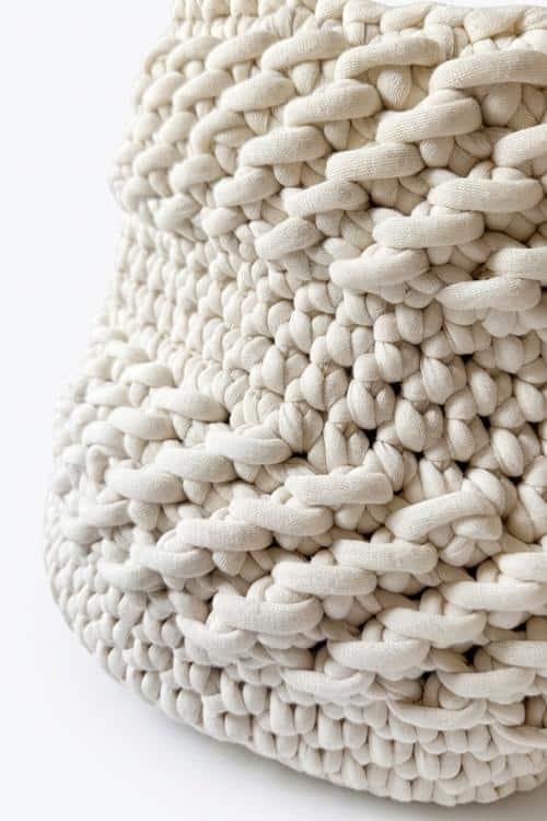 Close-up of a thickly woven, off-white fabric with a chunky, textured pattern. The yarn is soft and voluminous, giving the material a cozy and tactile appearance. Free crochet pattern