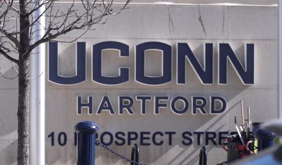 The UConn Hartford campus sign, with the university's name in bold blue letters. The address, 10 Prospect Street, is visible below. This image is relevant to a story about an education lawsuit, potentially involving issues with literacy and the Hartford public schools.