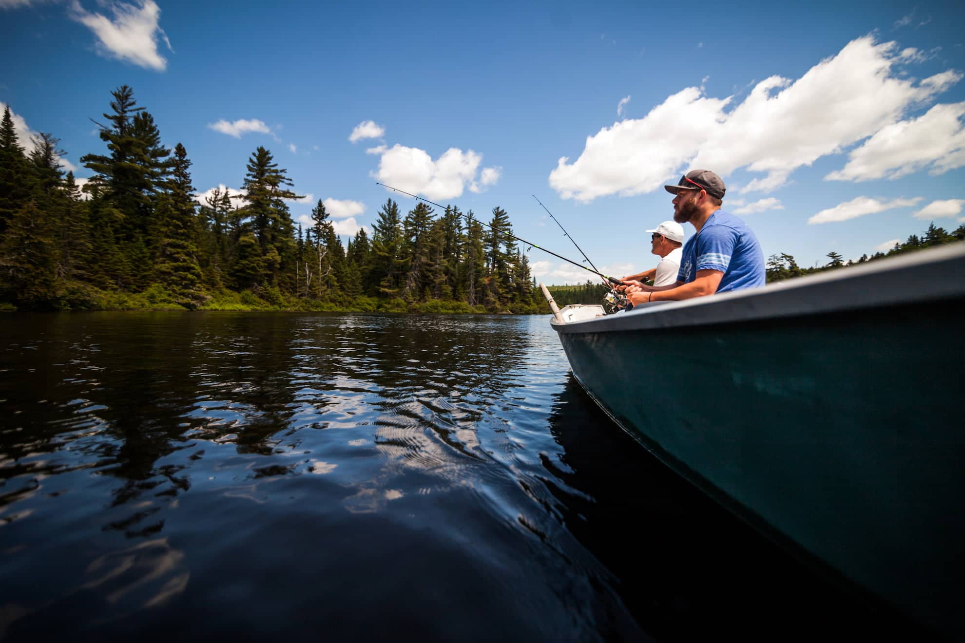 Father and two children fishing together in a boat on a lake surrounded by trees, representing outdoor family life near Morgan Maples Estates.