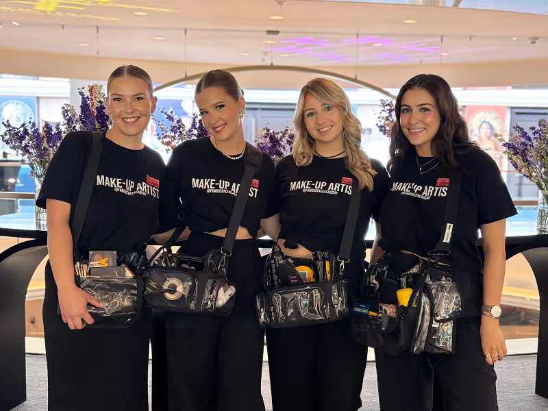 Vier Schülerinnen der Famous Face Academy mit Make-up Ausstattung lächeln in die Kamera