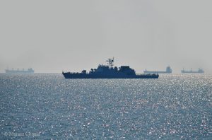 Nava de război pe mare la orizont Nava de război navigând pe mare, cu silueta clar vizibilă în lumina soarelui.